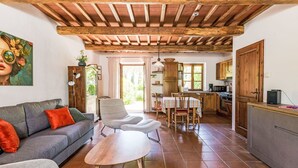 A cozy living room with a sofa, armchair, and coffee table, a kitchen with wooden cabinets, and a dining area with a table and chairs. - Cosy apartment for 4 people with WIFI, TV, patio, pets allowed and panoramic view (Gavorrano)