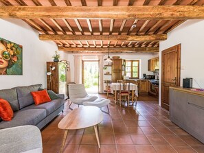 A cozy living room with a sofa, armchair, and coffee table, a kitchen with wooden cabinets, and a dining area with a table and chairs. - Lovely apartment for 4 guests with WIFI, TV, patio, pets allowed and panoramic view (Gavorrano)