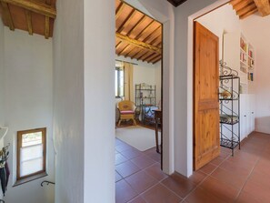 A hallway with a wooden door, a metal shelf unit, and a wicker chair. - Lovely apartment for 4 guests with WIFI, TV, patio, pets allowed and panoramic view (Gavorrano)