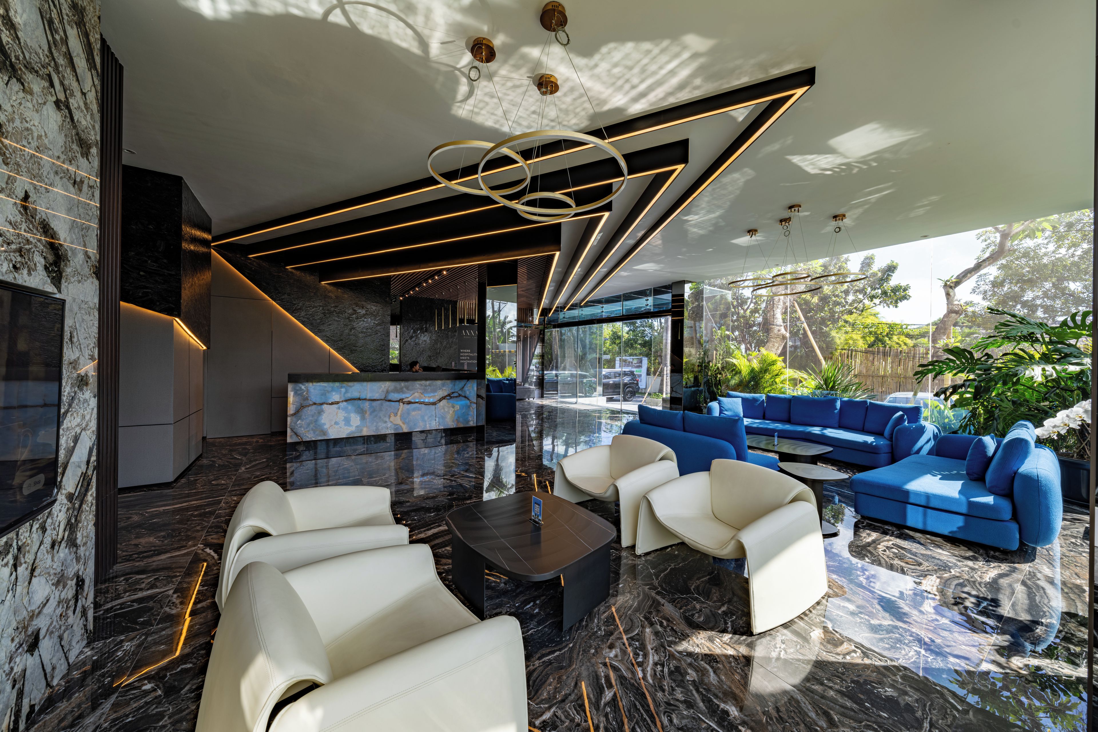 Un interior moderno con piso de mármol, un conjunto de sofá azul y un sofá de cuero blanco.