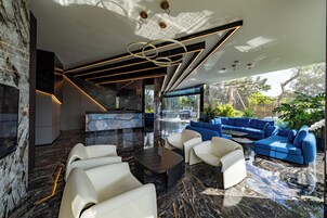 A modern interior with a marble floor, a blue sofa set, and a white leather couch.