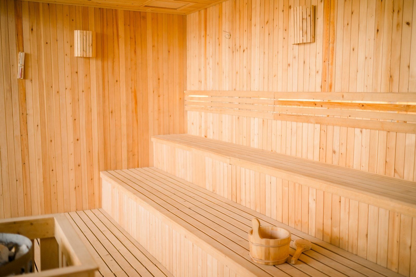 Eine Holzsauna mit Bänken und einem Holzeimer.