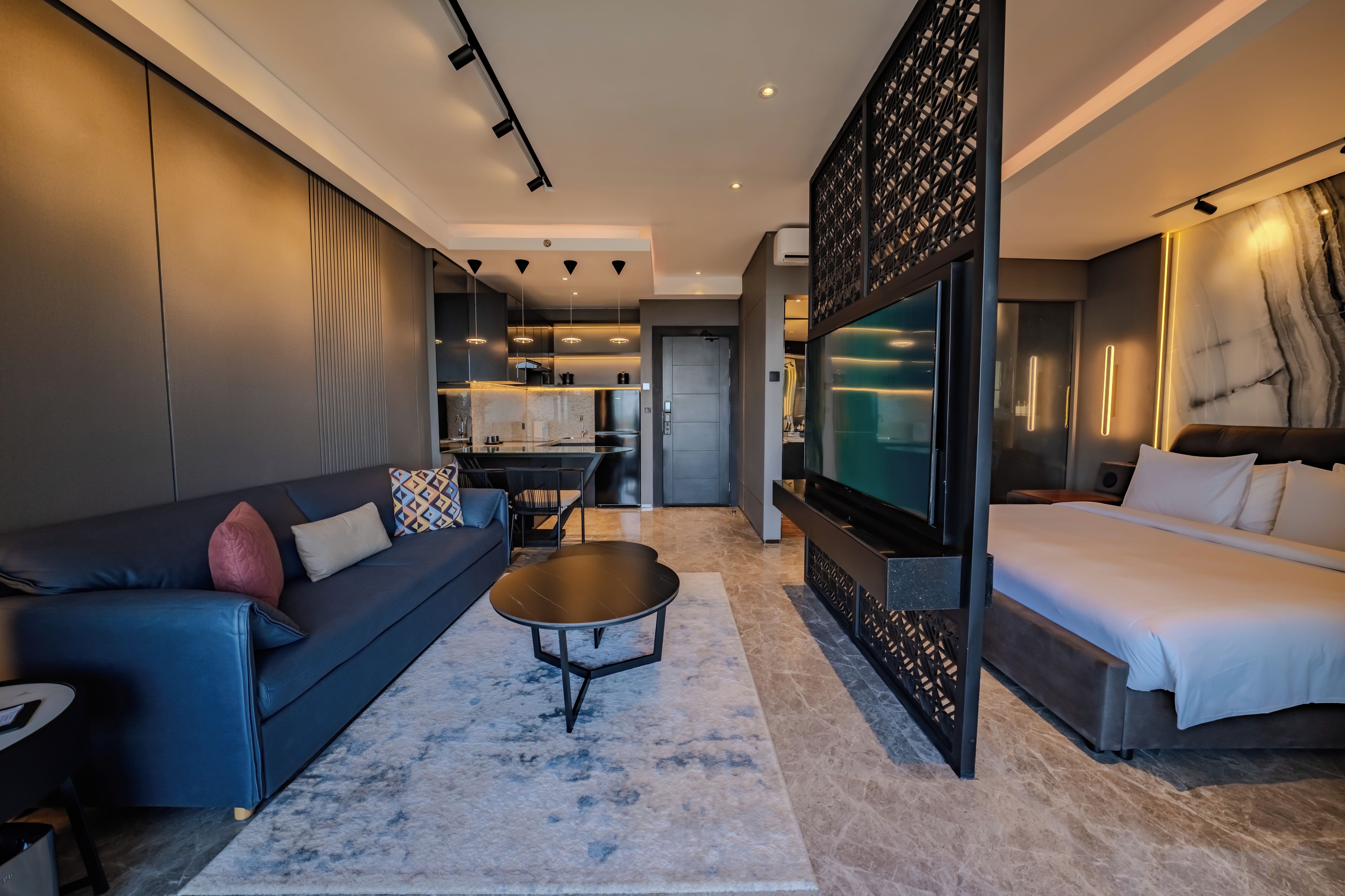Une chambre d’hôtel moderne équipée d’un canapé, d’une table basse, d’un téléviseur et d’un lit.
