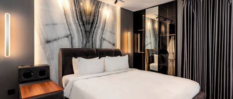 A modern bedroom with a large bed, built-in speakers, and a marble wall.