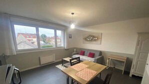 A compact living space with a dining table, chairs, a sofa, and a small table. - L'Héloïse, studio à Arras en résidence sécurisée (Arras)