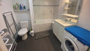 A compact bathroom with a toilet, shower, and washing machine. - L'Héloïse, studio à Arras en résidence sécurisée (Arras)