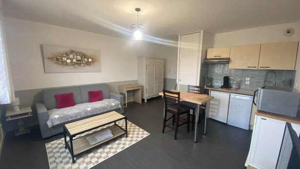 A compact living space with a sofa, a dining table, a kitchenette, and a ceiling fan. - L'Héloïse, studio à Arras en résidence sécurisée (Arras)