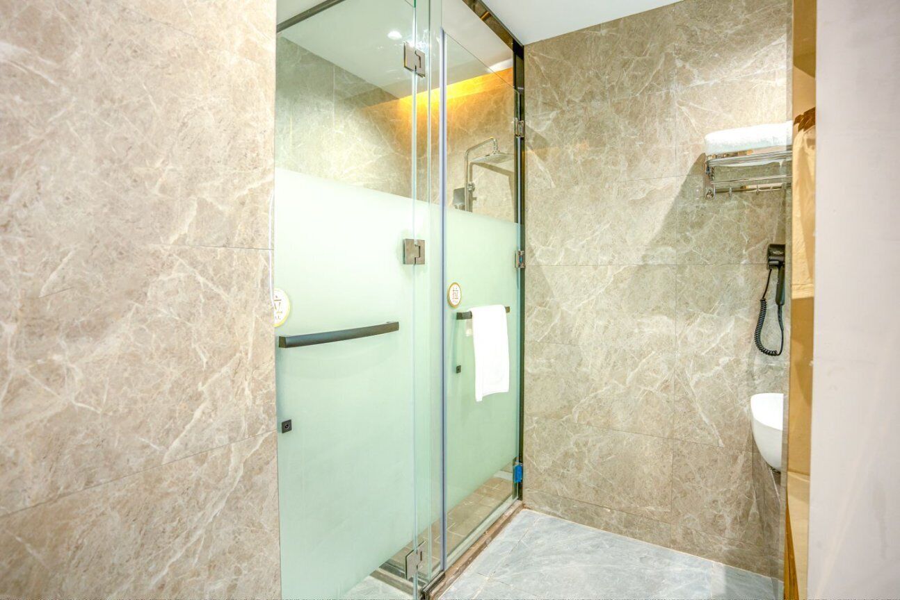 A modern bathroom with a glass-enclosed shower, marble walls, and a built-in sink.