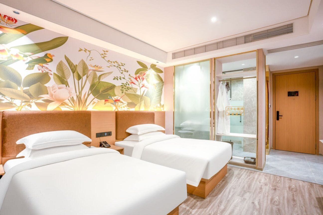 Camera d'albergo con due letti, un affresco floreale, una porta scorrevole in vetro e una porta in legno.
