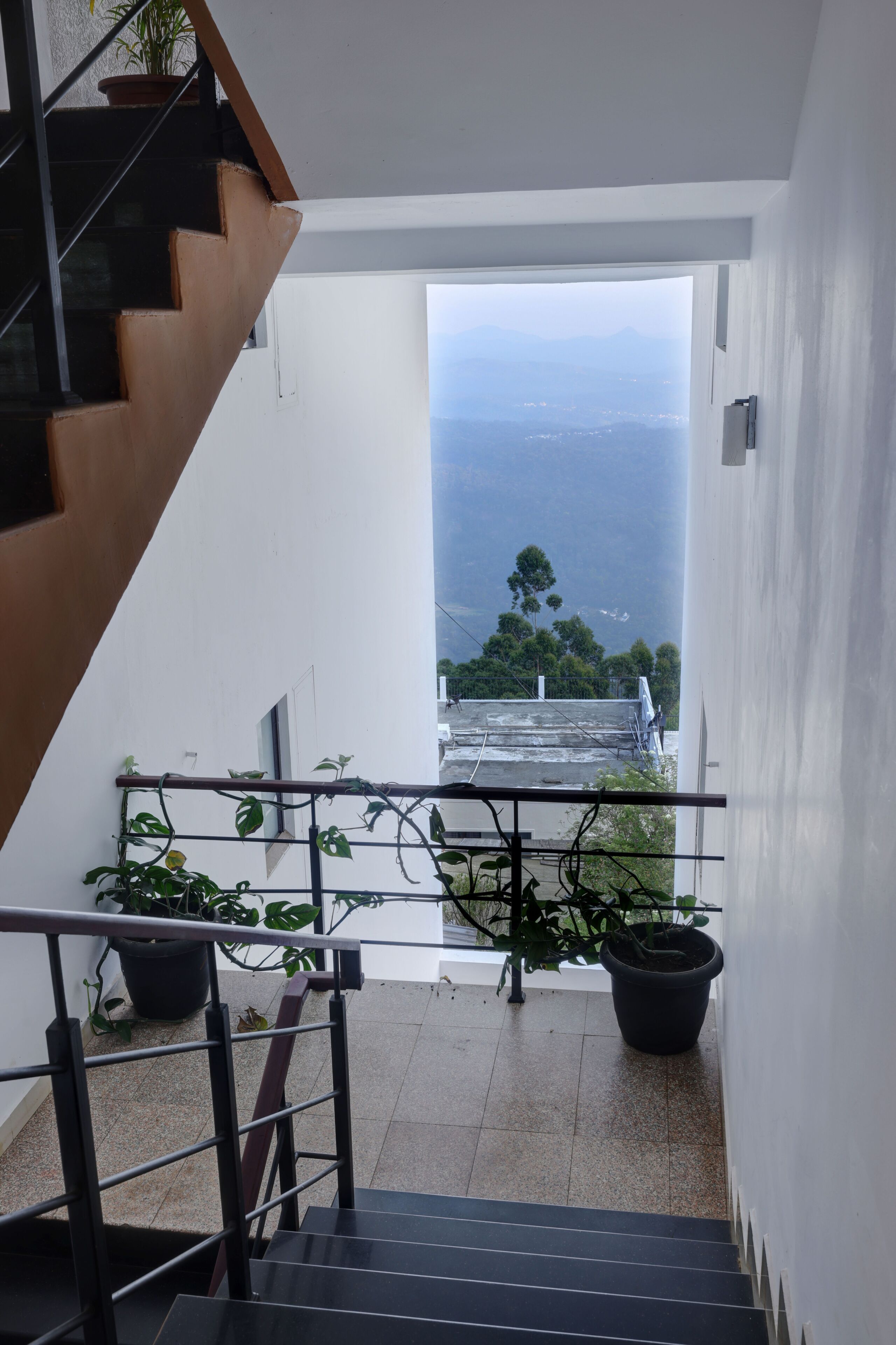 A staircase leading to a balcony with potted plants and a view of the city.