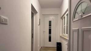 Ein schmaler Korridor mit einer Holztreppe zu einer Tür mit einer Milchglasscheibe.