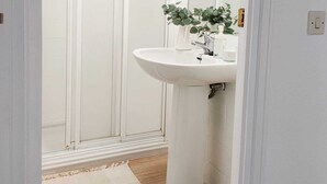 Une salle de bain avec un lavabo blanc, un miroir et une cabine de douche.