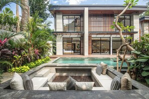 A modern two-story house with a swimming pool, outdoor seating area, and lush tropical plants. - Exquisite 5BR Modern Villa 400m From the Ocean (Seminyak)
