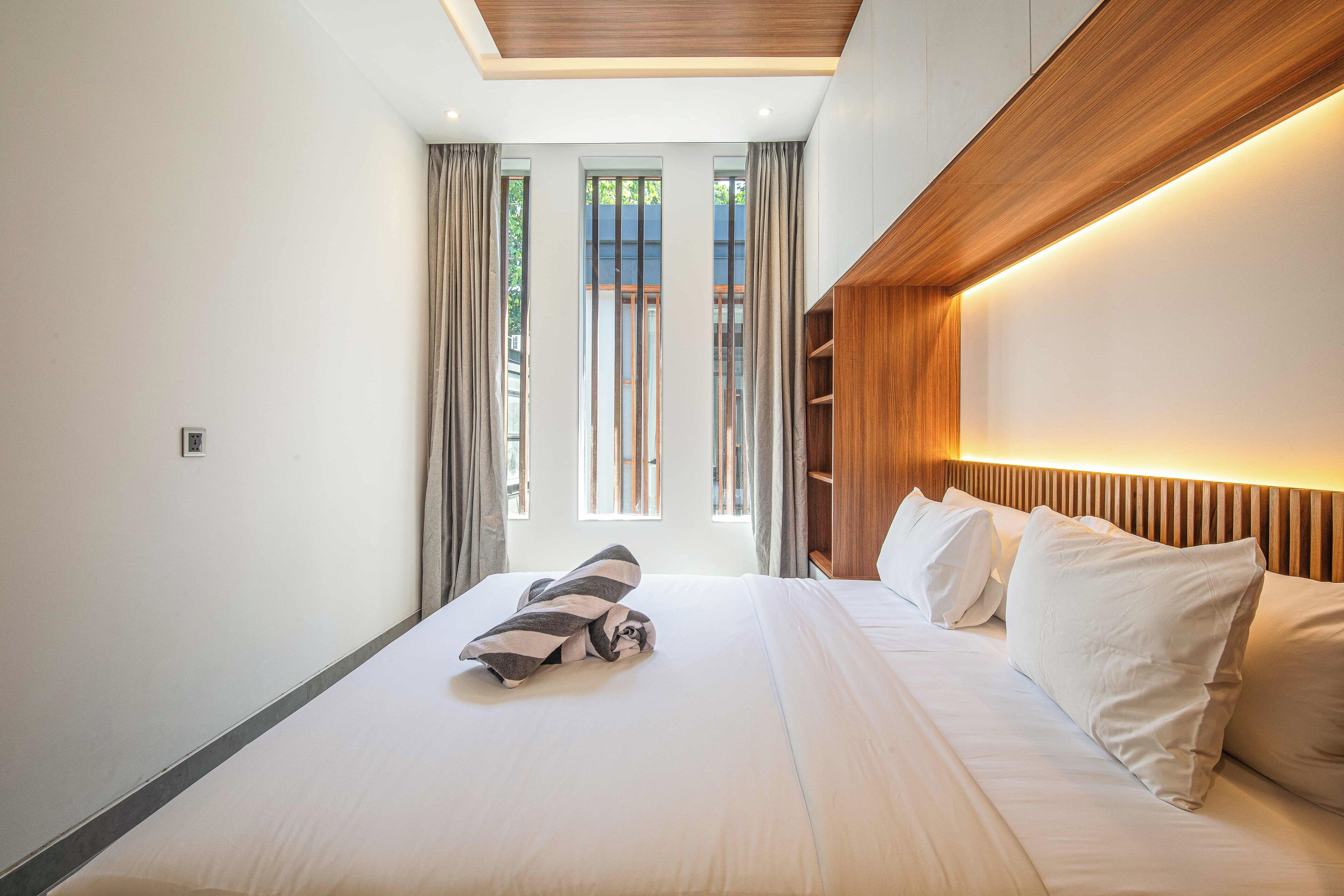 Een moderne hotelkamer met een groot bed, een houten hoofdeinde en een dakvenster.