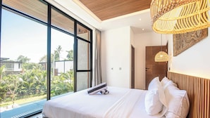 Un dormitorio moderno con una cama grande, vista a zonas verdes y una lámpara de fibra natural.