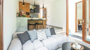 A modern living room with a sofa, a dining area, and a kitchen in the background. - Chic 1BR Villa Jungle Escape Heart of Ubud (Ubud)