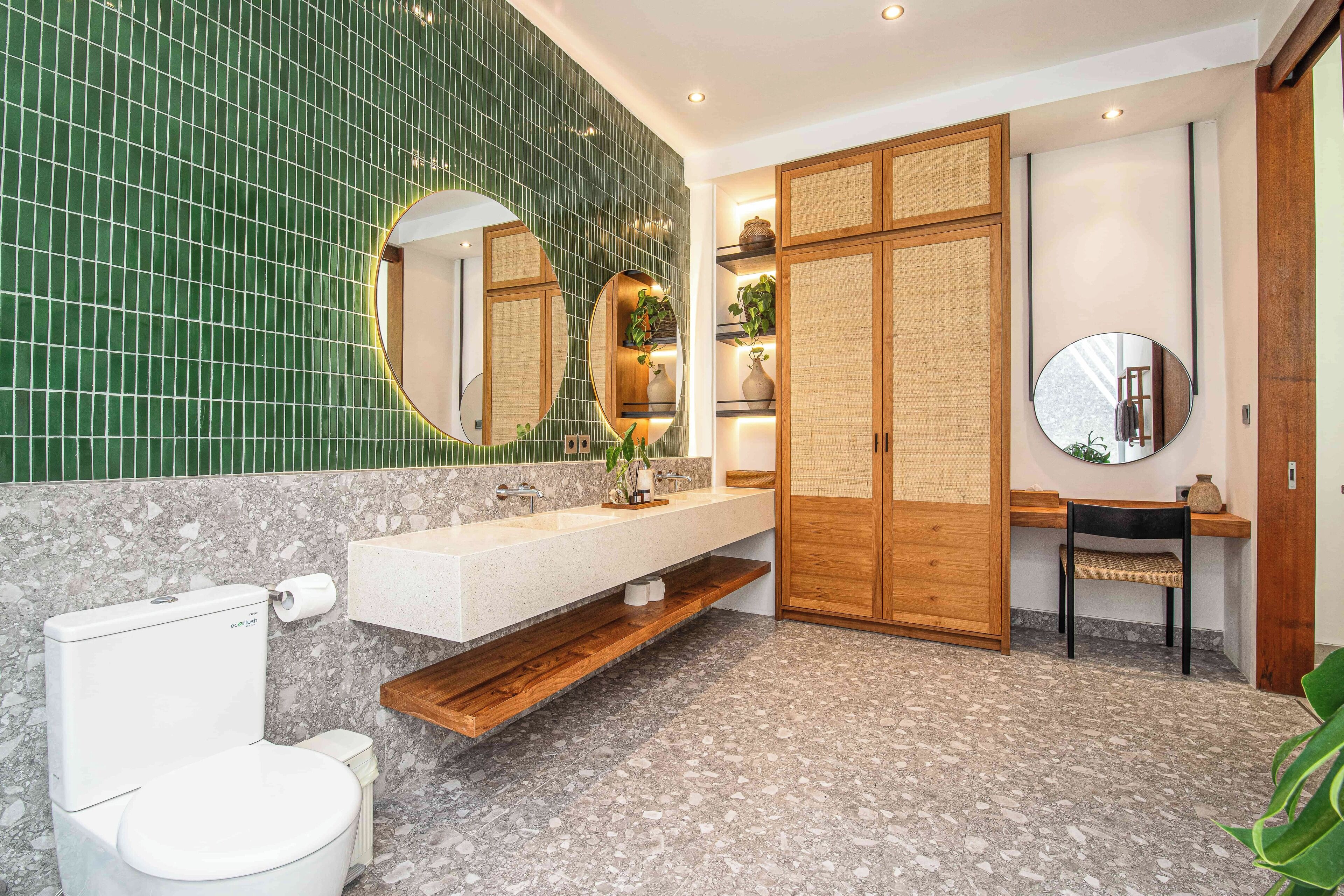 Ein modernes Badezimmer mit grüner Fliesenwand, einer weißen Toilette, einem Holzwaschtisch und einem Spiegel.