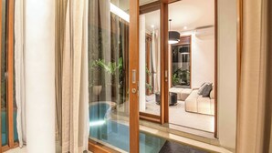 A modern interior with a glass door leading to a living area, a pool, and a sliding glass door. - Chic 1BR Villa Jungle Escape Heart of Ubud (Ubud)