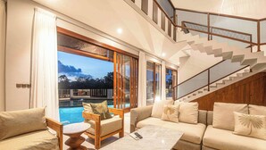 Una sala moderna con vista a la piscina, una escalera y un conjunto de sofás.