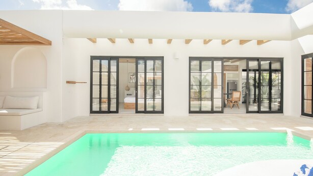 Une maison moderne dotée d’une piscine, de grandes portes-fenêtres coulissantes et d’un espace patio.