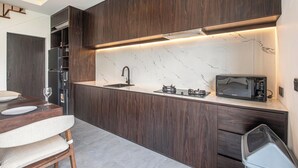 Een moderne keuken met donker houten kastjes, een marmeren aanrechtblad en een ingebouwde magnetron.