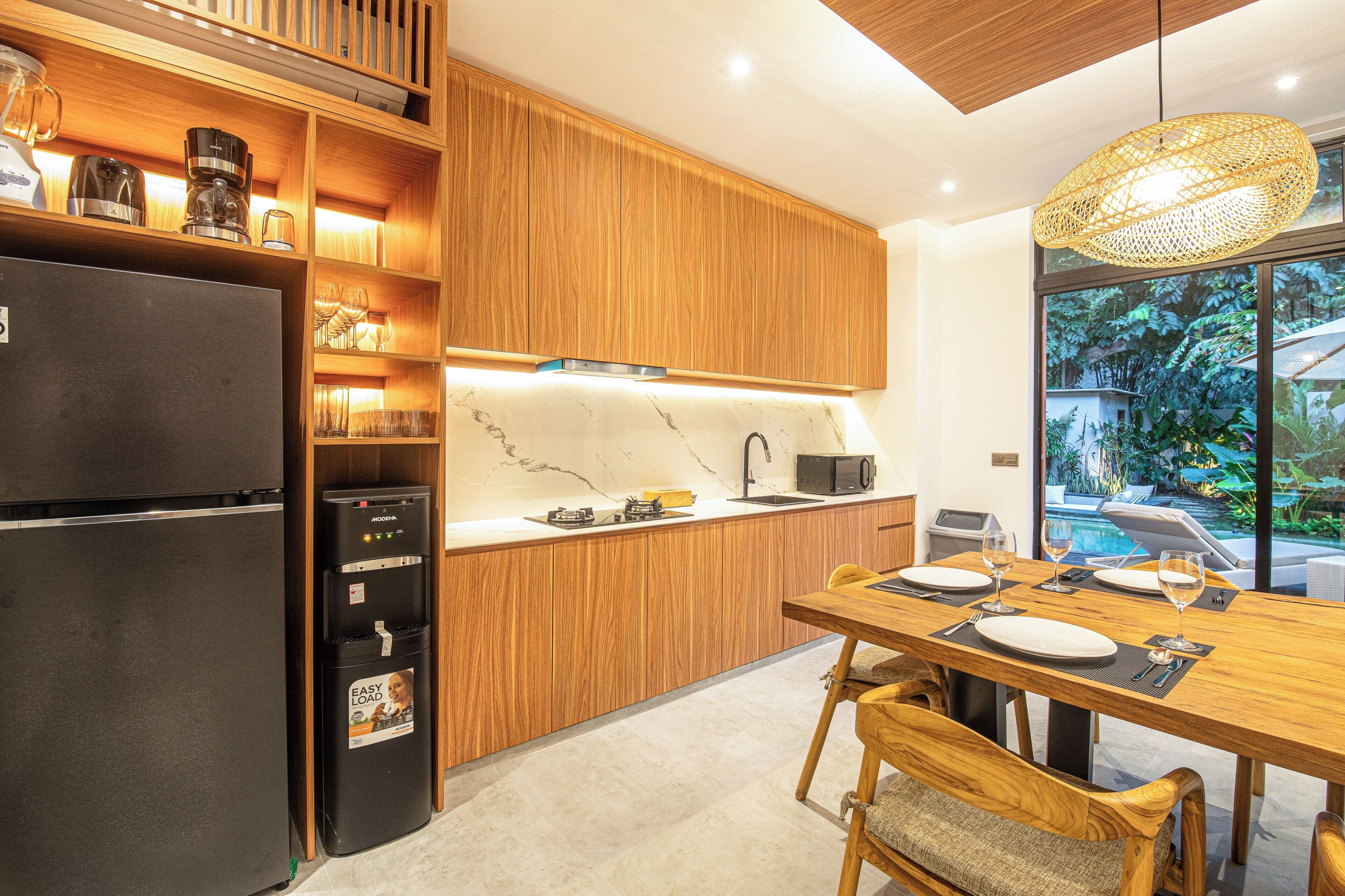 A modern kitchen with wooden cabinets, a built-in oven, and a dining area with a table and chairs.