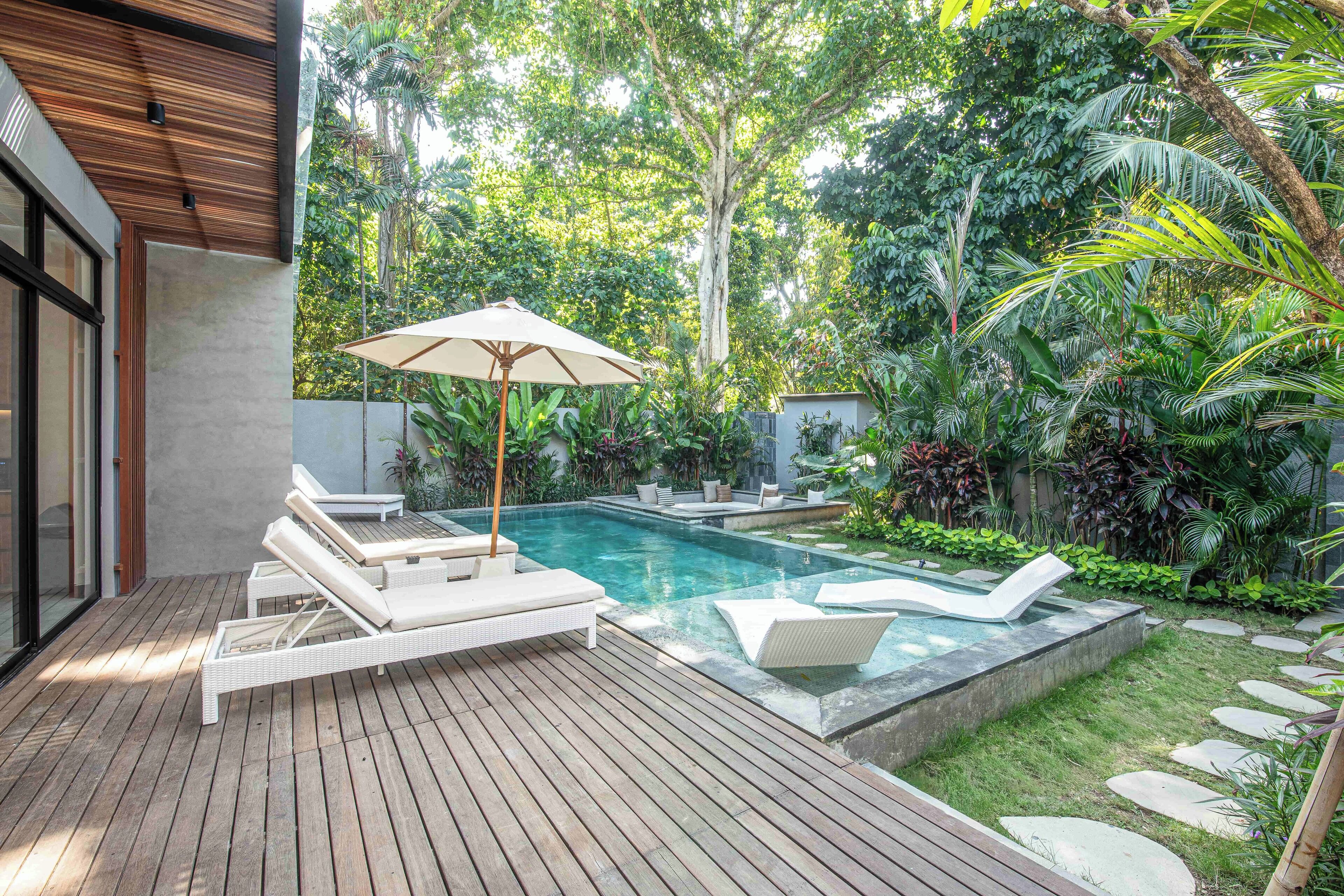 A modern outdoor pool area with lounge chairs and a wooden deck.
