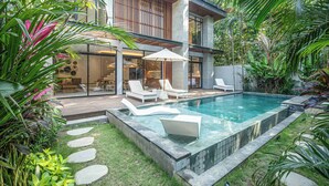 A modern house with a swimming pool, outdoor seating, and lush greenery. - Designer 5br Villa 400m to Caf del Mar (Seminyak)