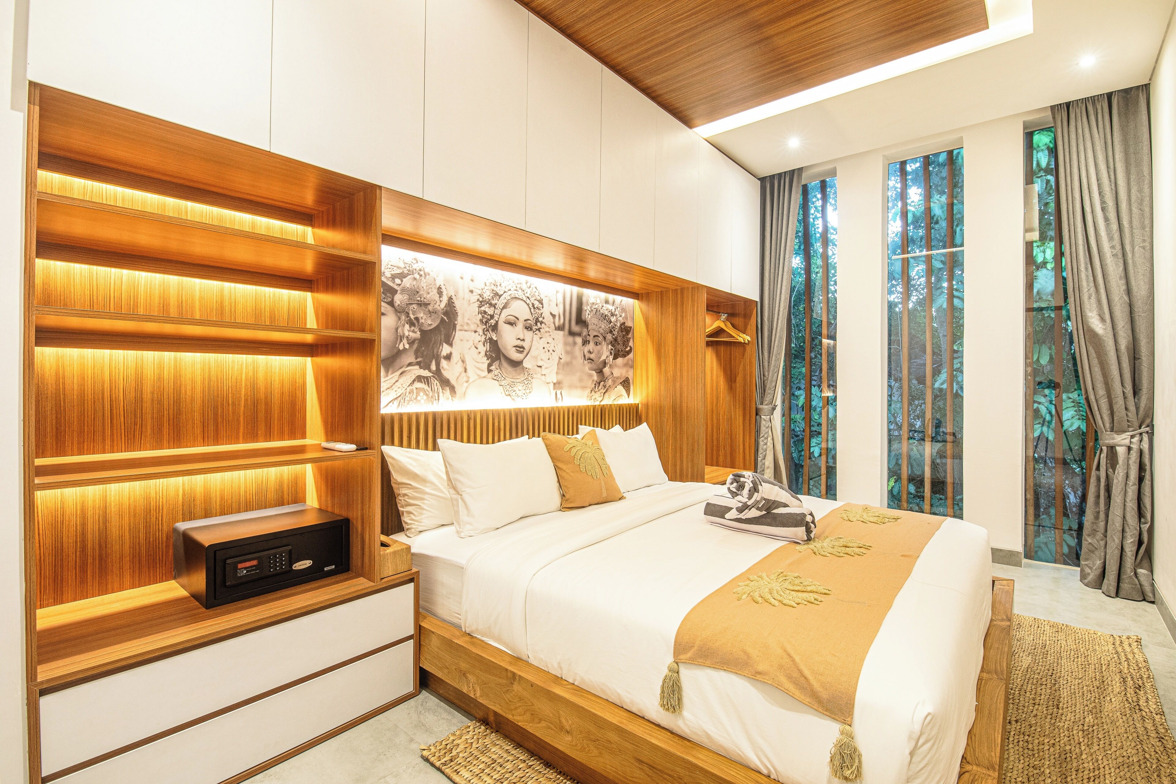 Un dormitorio moderno con cabecera de madera, mesita de noche con panel de control y un amplio ventanal con cortinas.