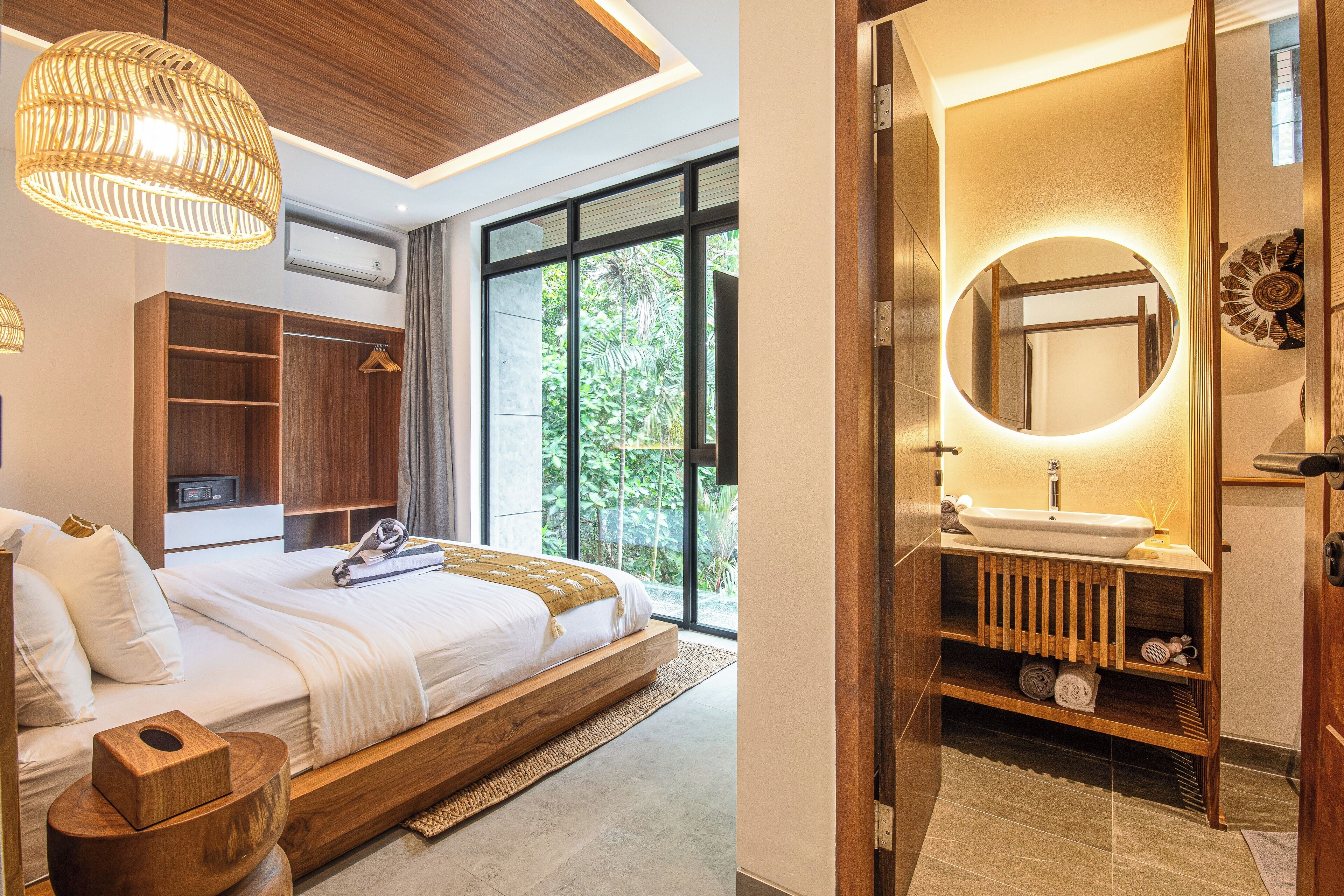 A modern bedroom with a large bed, built-in wardrobe, and a view of greenery.