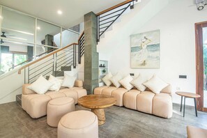 Ein modernes Wohnzimmer mit einer Eckcouch, einem Holztisch und einer Treppe mit Glastrennwand.