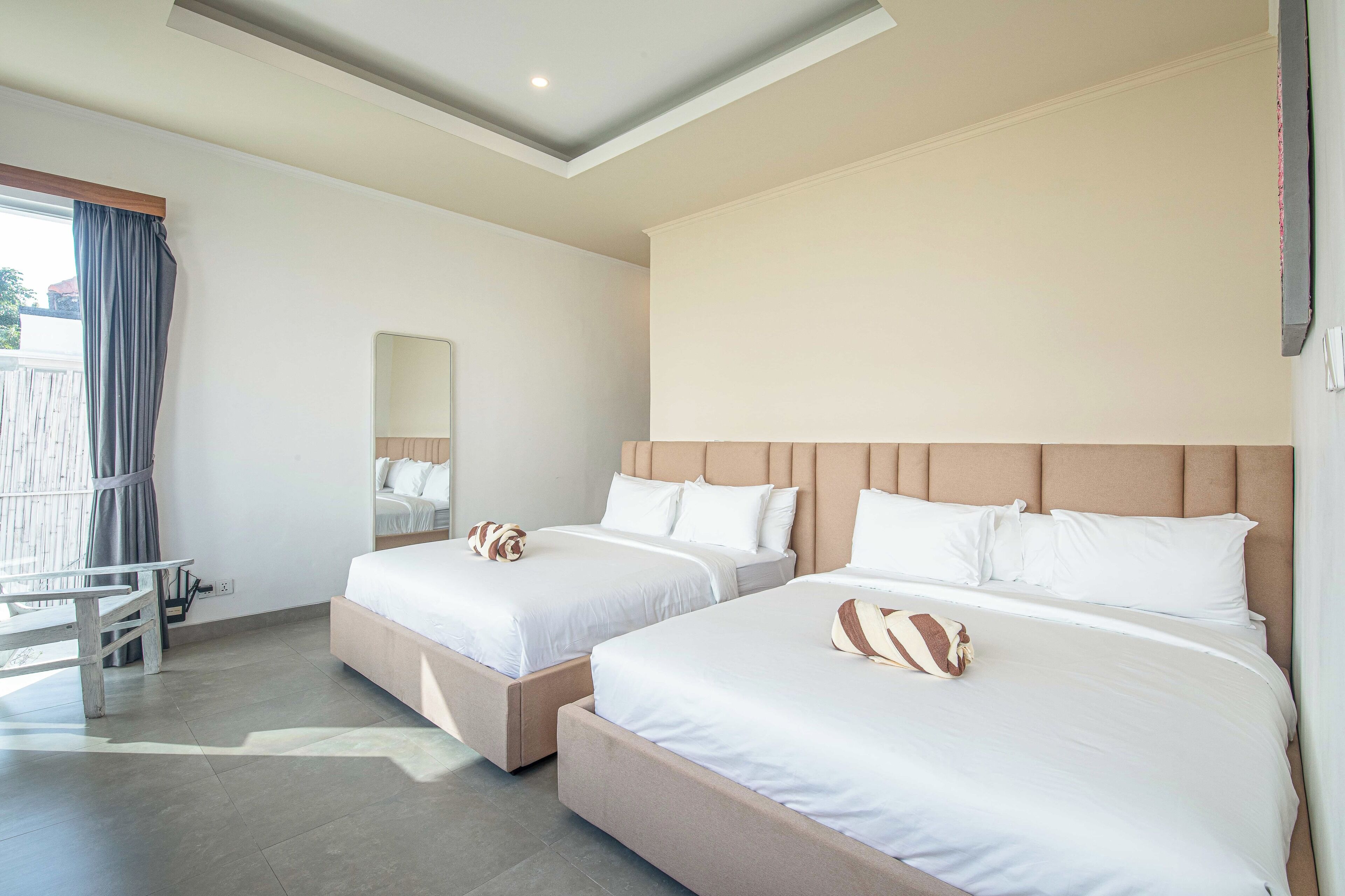 Habitación de hotel con dos camas, un escritorio y un ventanal grande con cortinas.