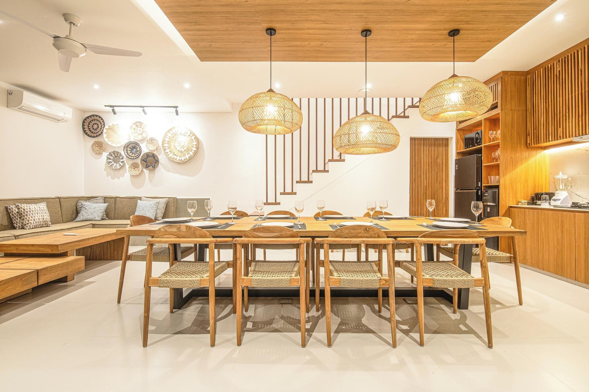 Une cuisine moderne avec un coin repas, comprenant une table à manger en bois, des chaises et des luminaires suspendus.