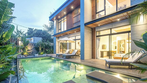 A modern house with a swimming pool, lounge chairs, and a well-lit outdoor area. - Elegant 5BR Modern Villa Steps From Caf Del Mar (Seminyak)