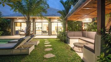 Een modern huis met een zwembad, terras en een keurig onderhouden tuin.