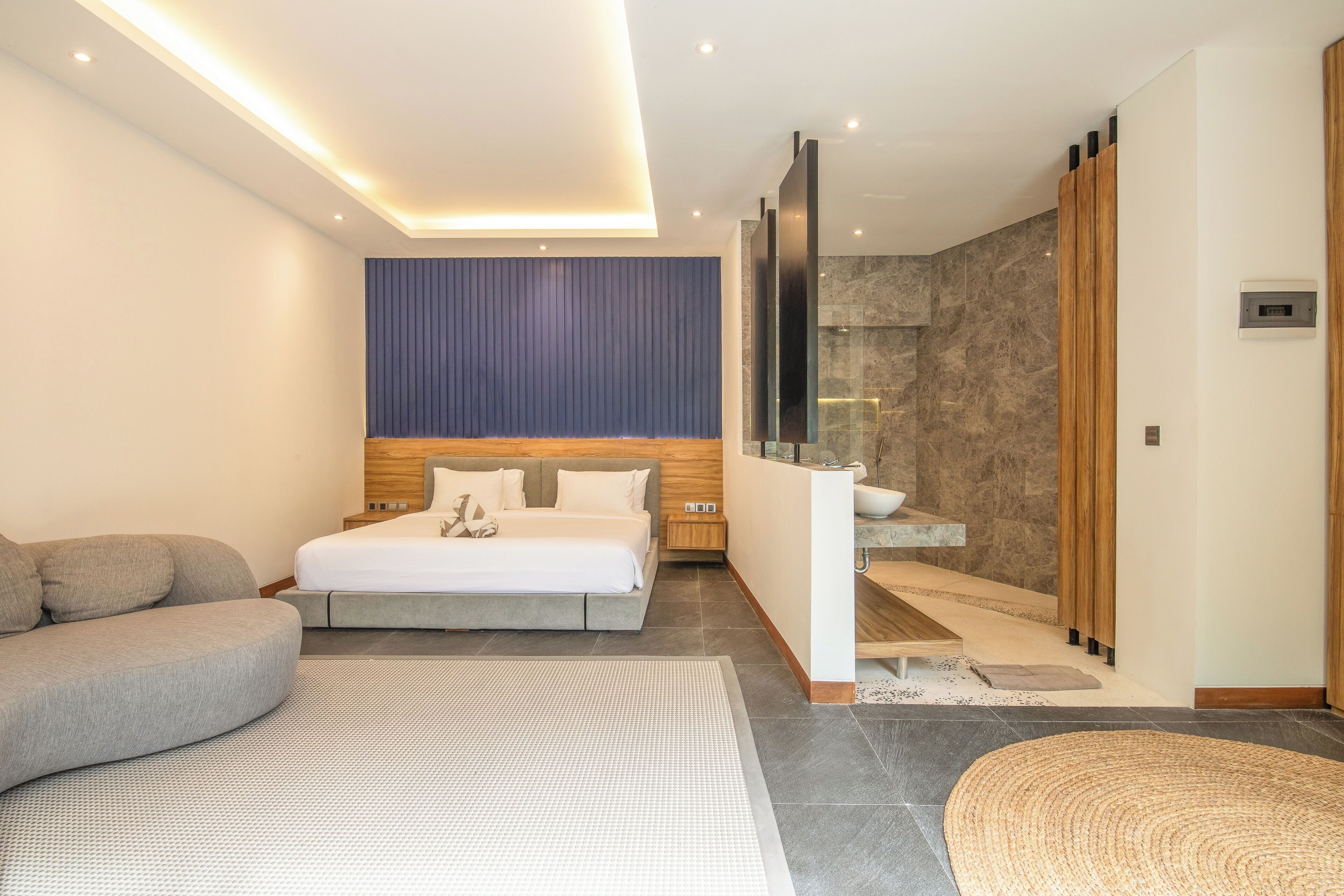 Een moderne slaapkamer met een bed, een bank, een badkamer met douche en een trap.