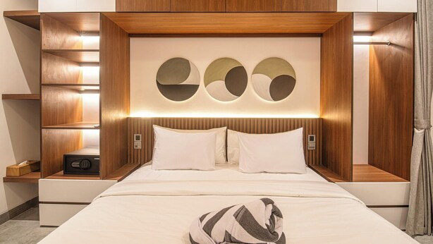 A modern hotel room with a wooden headboard, a bed with white linens, and built-in shelves with lighting. - Sophisticated 5-br Canggu Retreat Near Beach (Canggu)