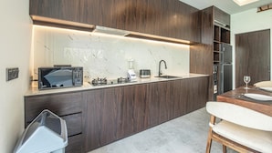 A modern kitchen with dark wood cabinetry, a marble backsplash, and a built-in stove. - Sophisticated 5-br Canggu Retreat Near Beach (Canggu)