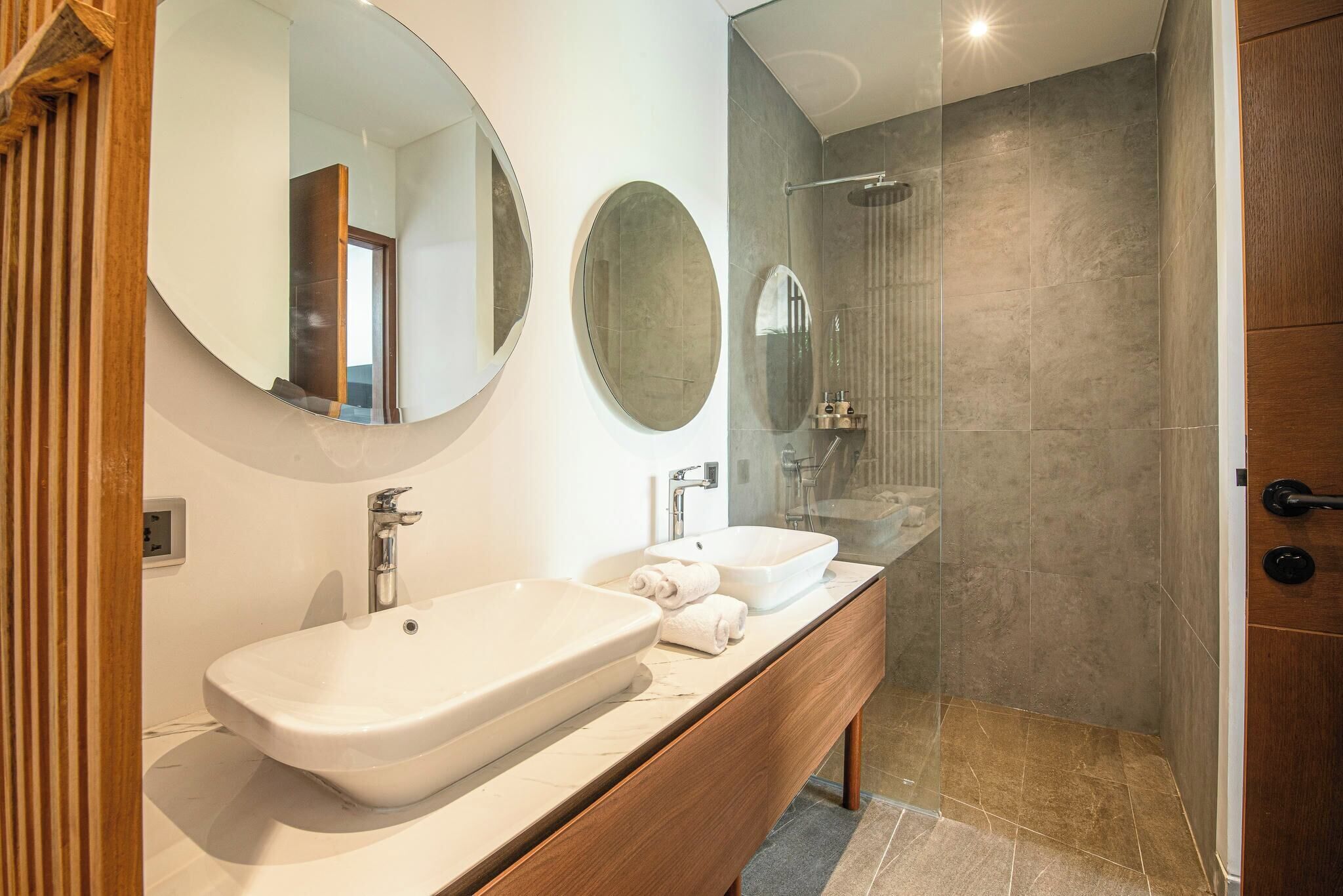 Un baño moderno con dos lavamanos, un espejo grande y una zona de ducha.