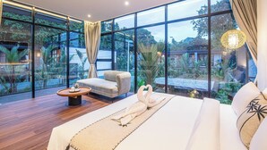 A modern bedroom with a large window, a bed, a sofa, and a coffee table. - Elegant 6BR Canggu Villa Steps From the Ocean (Seminyak)