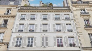 En byggnad med flera våningar, vitmålade fönsterluckor, balkonger med smidesjärnsräcken och en klassisk arkitekturstil.