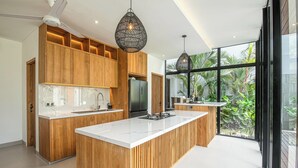 Una cucina moderna con mobili in legno, una grande isola e illuminazione a sospensione.