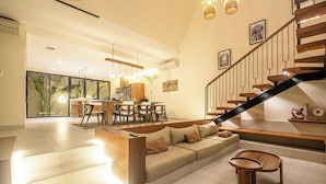 A spacious living area with a sofa, coffee table, and a staircase. - Elegant 4BR Seminyak Villa 10min From the Shore (Seminyak)