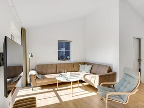 A modern living room with a large sofa, a coffee table, a chair, a TV, and a window. - "Eida" - 500m from the sea by Interhome (Løkken)