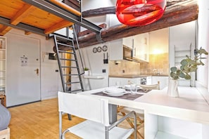 Een moderne keuken met witte kasten, een houten plafond en een eethoek met een witte tafel en stoelen.