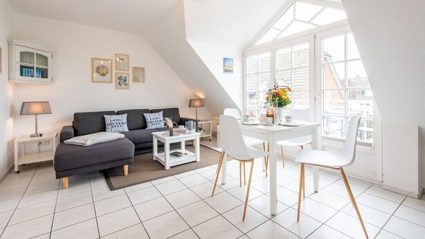 A modern loft apartment with a dining area, a sofa, and a view through large windows. - Syltperle, Germany (Sylt)