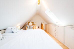 A bedroom with a sloped ceiling, a bed, a wardrobe, and a skylight. - Syltperle, Germany (Sylt)