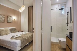 Ein modernes Schlafzimmer mit einem großen Bett, einer Duschkabine und einem kleinen Badezimmer.
