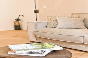 A living room with a sofa, a coffee table with a book, and a decorative vase. - New flat with AC Porte Maillot/Arc de Triomphe (Paris)