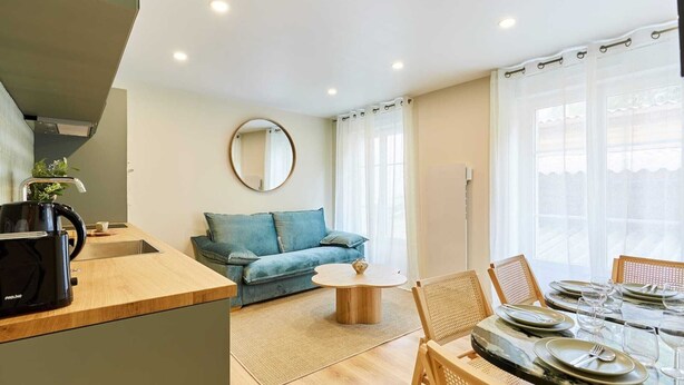 Una sala de estar moderna con un sofá, una mesa de centro y una zona de comedor preparada para cuatro.